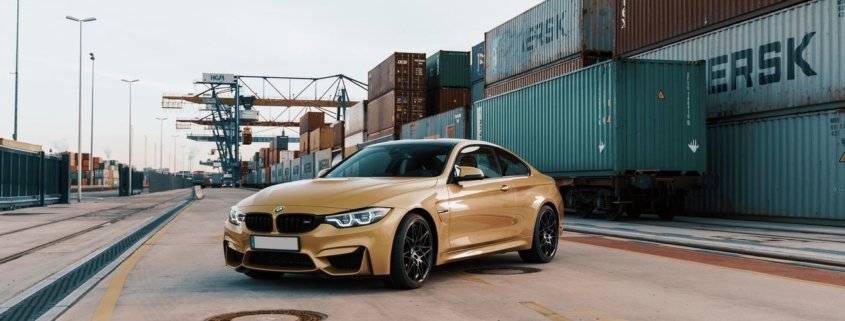 Wer fährt welchen Firmenmietwagen: goldener BMW Firmenwagen vor Industriecontainer