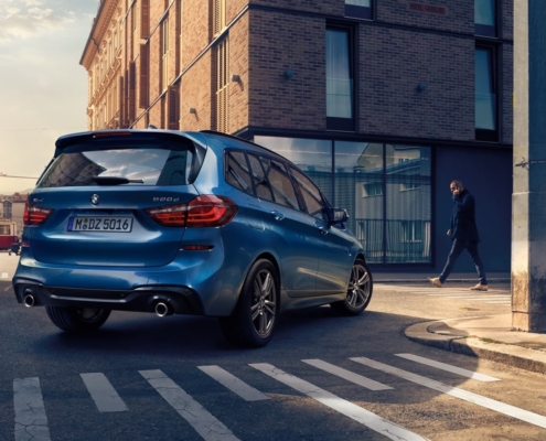 Firmenwagen im Auto Abo vs. Autokauf - blauer BMW Kombi fährt durch Innenstadt