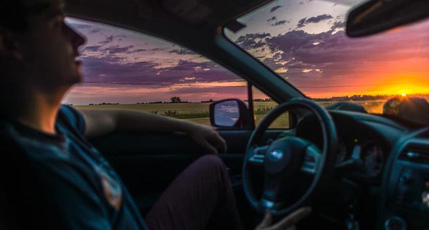 Mann im Auto bei Sonnenuntergang