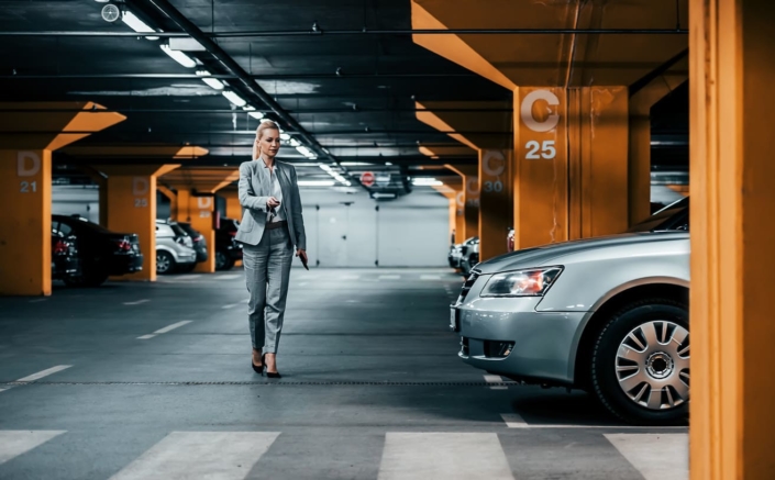 Betriebliche Mobilität - Geschäftsfrau öffnet Auto im Parkhaus