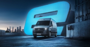 Silberner E-Transporter Mercedes vor großem, neonblauen, leuchtendem E