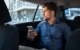 Business man is sitting in a car and using his smartphone